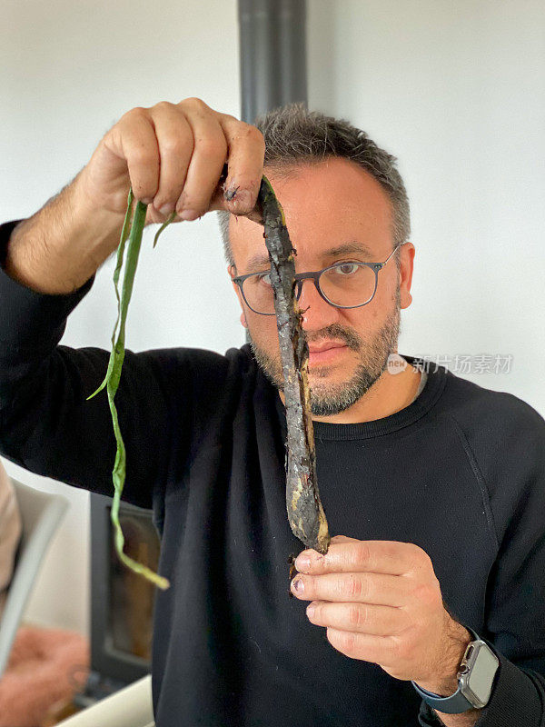 Man willing to peel and eat a ‘calçot’, a kind of roasted spring onion or scallion